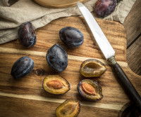 Un couteau et des prunes ouvertes en deux
