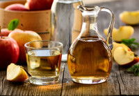 Du vinaigre de cidre dans un flacon en verre, avec des pommes