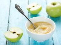 De la compote dans un bol avec des pommes sur une table bleue