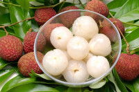 Des litchis pelés dans un bol en verre sur des feuilles