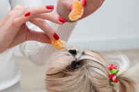 Une femme donne des quartiers de mandarine à un petit chien