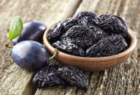 Des pruneaux dans une soucoupe sur une table en bois