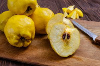 Des coings en morceaux avec un couteau sur une planche de cuisine