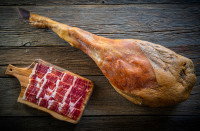 Un jambon entier de porc avec des tranches de jambon cru