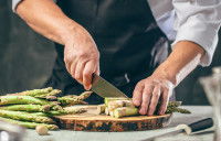Un cuisinier découpe des asperges en petits morceaux