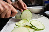 Une femme découpe une courgette en fines tranches