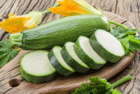 Une courgette entière et en tranche sur une planche en bois