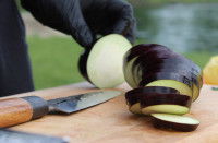 Un homme coupe une aubergine en tranches avec un couteau