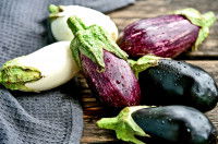 Des aubergines de différentes couleurs sur une table en bois