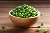 Des petits pois dans un bol sur une table de bois