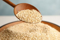 Une cuillère de bois verse du quinoa dans une assiette