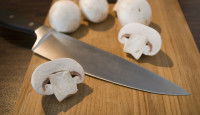 Des champignons de Paris sur une planche de bois avec un couteau
