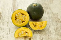 Une courge entière et ouverte en deux sur un fond en bois