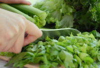 Une femme découpe du céleri avec un couteau