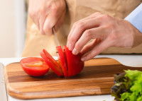 Un homme coupe une tomate avec un couteau