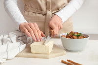 Une femme en train de découper du tofu