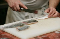 Un cuisinier découpe du poisson avec un couteau