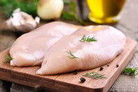 Des filets de poulet crus sur une planche en bois