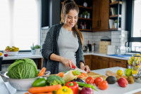 Une femme coupe des légumes pour préparer un repas maison