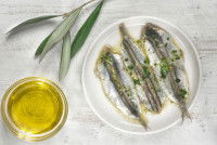Des filets de sardine dans une assiette à côté d'un bol d'huile