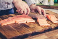 Un homme découpe du saumon avec un couteau