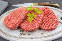 Trois steaks hachés crus dans une assiette