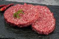 Deux steaks hachés crus sur une plaque noire