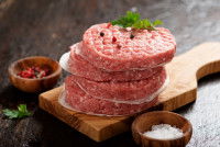 Des steaks hachés crus sur une planche de bois