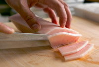 Une femme découpe un pavé de thon en tranches