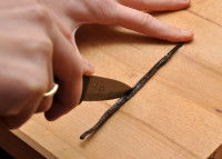 Un homme découpe une gousse de vanille avec un couteau