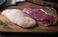 De la viande blanche et de la viande rouge posées sur une planche de bois