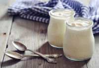 Deux yaourts nature dans des pots en verre avec des cuillères