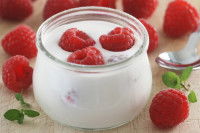 Un yaourt avec des framboises dans un pot en verre