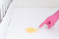 Une femme nettoie une tache de pipi sur le lit