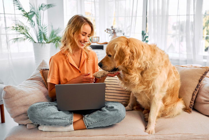 Une femme et son Golden Retriever assis côte à côte sur le canapé
