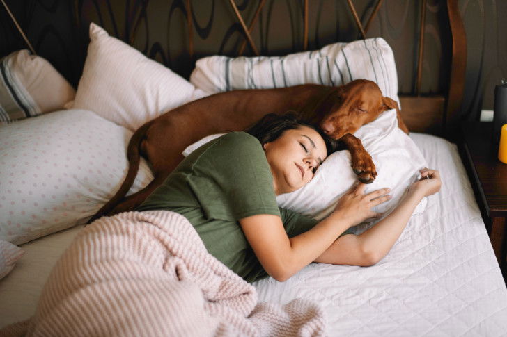Une femme dort avec son chien