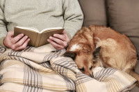 Homme lisant un livre avec son chien blotti contre lui