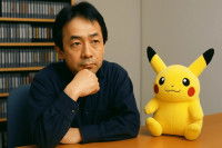 Satoshi Tajiri assis à une table à côté d'une peluche de Pikachu