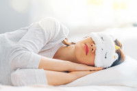 Une femme allongée en train de dormir avec un masque sur les yeux