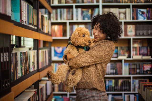 Une jeune femme et son chien dans une bibliothèque