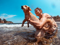 Une femme tient son chien dans ses bras pendant la baignade