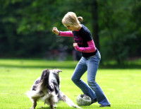 Une femme joue au foot avec son chien dans un parc