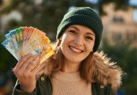 Une femme qui sourit en tenant dans les mains différents billets en francs suisses