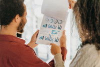Un homme et une femme en train d'étudier des documents comportant des graphiques