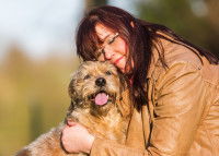 Une femme dog-sitter fait un câlin au chien qu'elle garde
