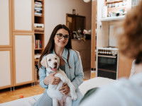 Une femme assise sur un canapé, serrant un chien dans ses bras et souriant à une autre personne en face d'elle