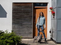 Une femme se tenant devant la porte d'entrée d'une maison avec un chien en laisse