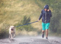 Un homme promenant un chien en laisse sous la pluie