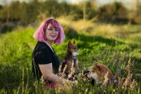 Portrait de Roxane Lasseur, assise dans l'herbe entourée de deux chiens