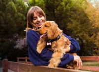 Une femme souriante qui tient dans ses bras un Cocker